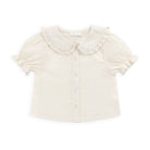 An off-white baby girl's blouse with a ruffled Peter Pan collar, short puff sleeves, and a button-up front, shown flat on a white background.