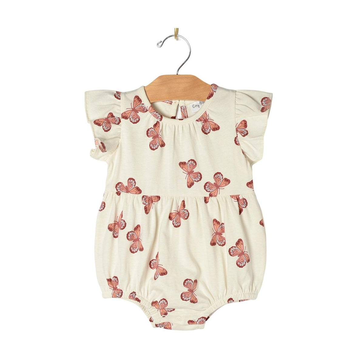 A baby romper in cream with a red butterfly pattern, hanging on a wooden hanger against a white background.