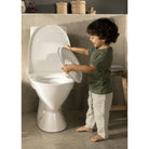 Child interacting with a white toilet in a bathroom setting