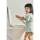 Child interacting with a laptop on a white surface