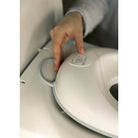 Hand pressing a button on a white appliance with a brand logo.