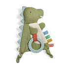 A plush dinosaur baby toy in sage green and light blue, featuring a striped bib, a light blue rope ring, and colorful fabric tabs in blue, green, yellow, orange, and red, set against a plain white background.