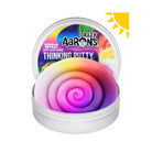 A round tin of Crazy Aaron's Thinking Putty with the lid partially open, showing a rainbow-colored spiral putty inside. The packaging features a colorful label and a yellow sun icon in the top right corner, all on a solid white background.