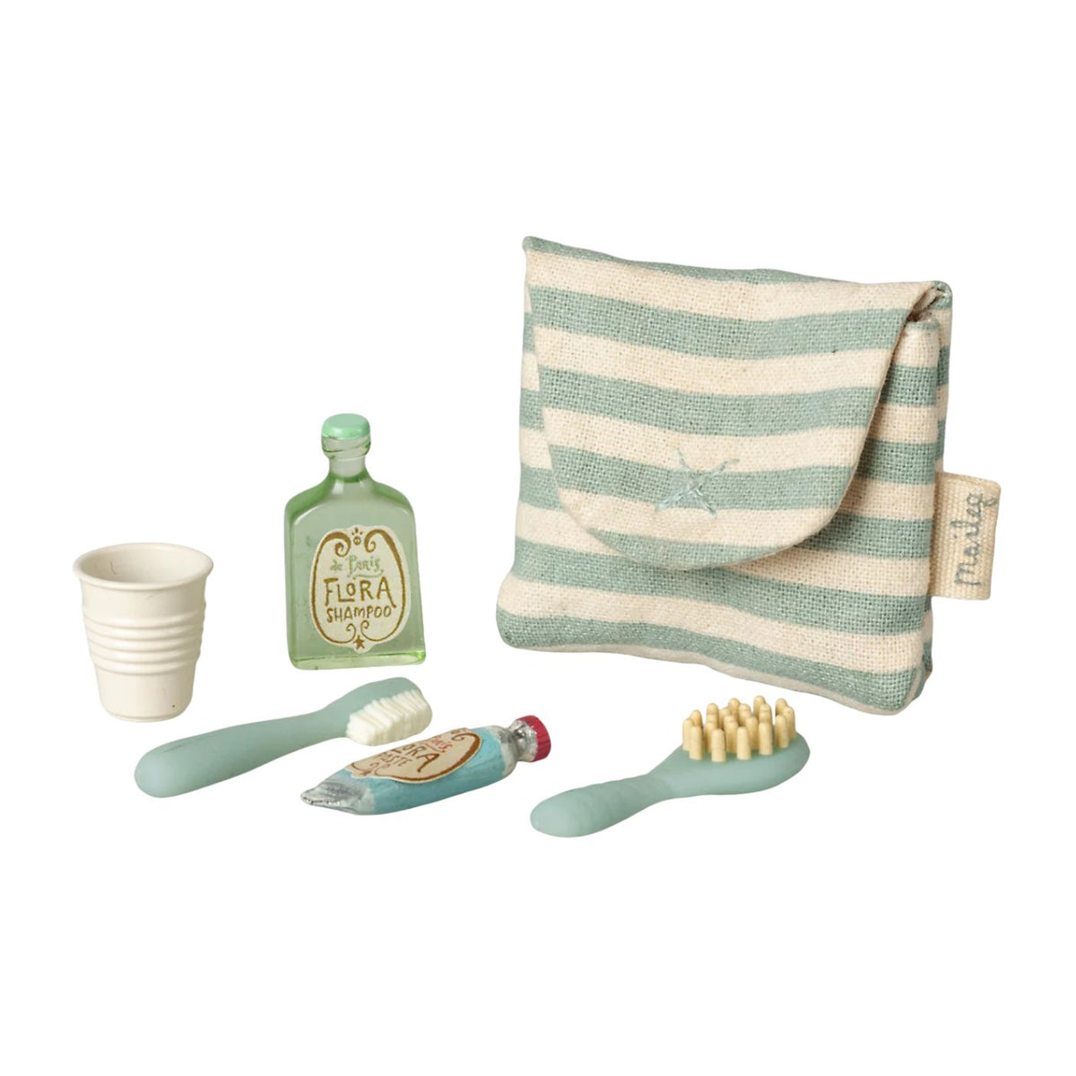 A miniature dollhouse-style toiletry set on a white background, including a striped fabric pouch, a small green bottle labeled Flora Balneum, a white cup, a toothbrush, a tube of toothpaste, and a hairbrush.
