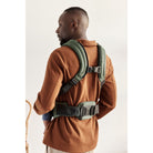 Man wearing a green backpack on a plain background