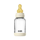 Clear baby bottle with beige cap and base on a white background