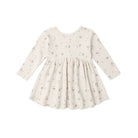 A long-sleeve baby dress in cream with a delicate all-over floral print, featuring a gathered waist and flared skirt, shown against a plain white background.