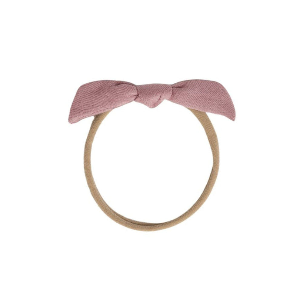 A dusty pink fabric bow headband with a tan elastic band, shown against a plain white background.