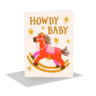 A baby greeting card with a whimsical rocking horse illustration and the text 'HOWDY BABY' in gold lettering, shown standing upright with a gray envelope behind it on a white background.