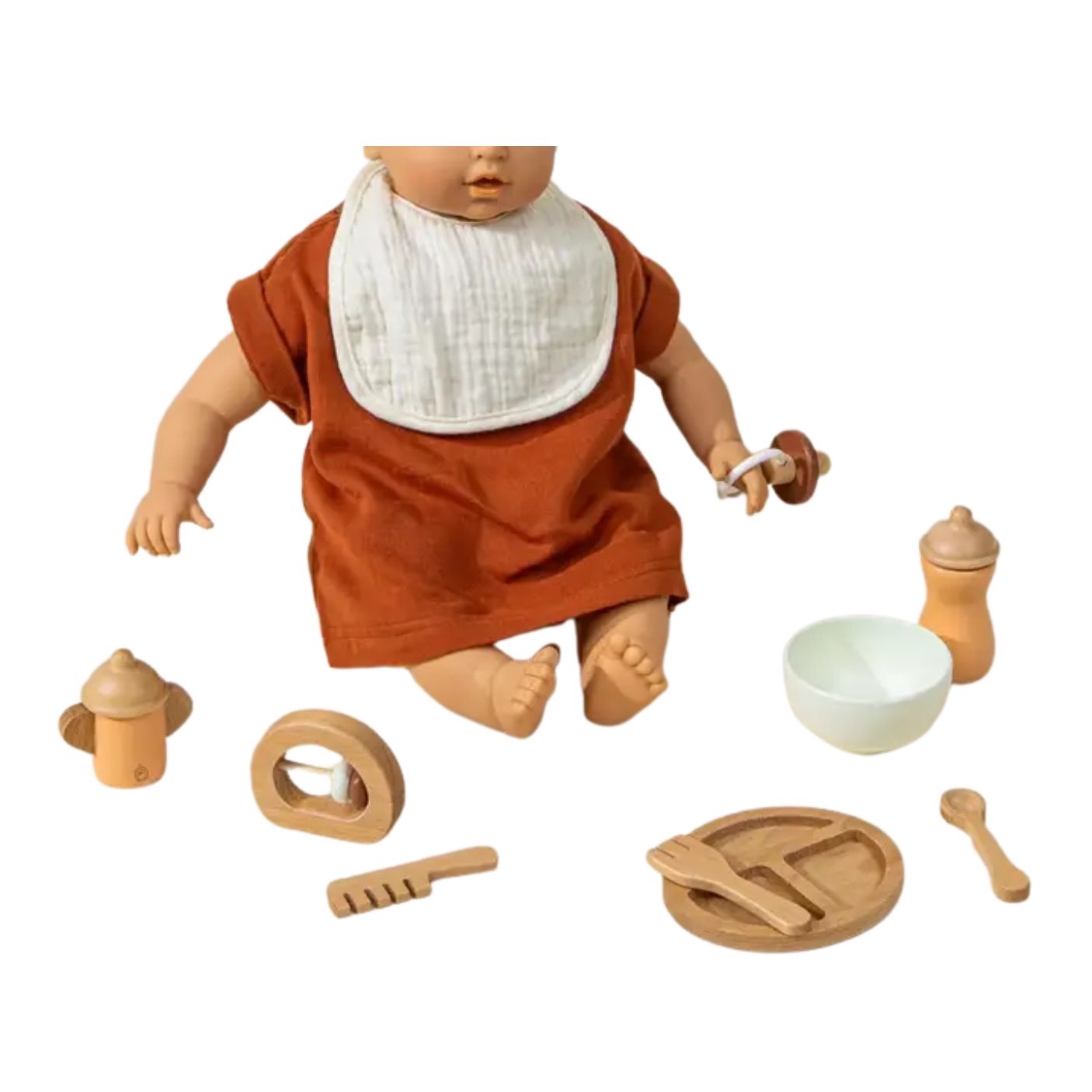 A wooden baby doll dressed in a rust-orange tunic and white bib, surrounded by matching wooden feeding accessories including a bottle, sippy cup, bowl, spoon, pacifier holder, and plate, on a white background.