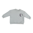 A light gray long-sleeve crewneck sweatshirt with a small dark gray graphic on the left chest, displayed flat against a solid white background.