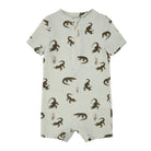 A short-sleeve baby romper in a light sage green color, featuring an allover print of dark brown alligators and small orange reeds. The romper has a short front zipper and is displayed flat against a solid white background.