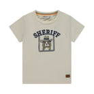 A light beige short-sleeve t-shirt with a 'SHERIFF' graphic featuring a cartoon dog in a cowboy hat. The brand name 'Right-Brown' is visible on the inner neck label and as a small brown patch on the lower right hem.