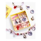 A children's bead and charm craft kit displayed in an open yellow box, surrounded by completed heart-themed bead garlands and charms on a white background.