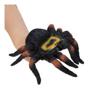 A realistic fake tarantula spider worn as a wrist glove on a person's wrist, shown against a plain white background.