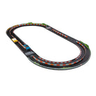 A slot car racing track set with a black oval layout, red and white striped barriers, green grass accents, and two toy cars, shown on a plain white background.
