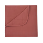 A folded terracotta-colored fabric napkin with a stitched curved edge, shown on a plain white background.