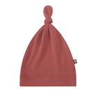 A dusty rose knit beanie hat with a knotted top and a small black brand tag on the side, shown against a plain white background.