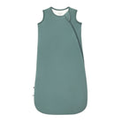 A sleeveless baby sleep sack in a muted sage green color, featuring a diagonal zipper and a small black tag near the bottom left hem, shown against a plain white background.