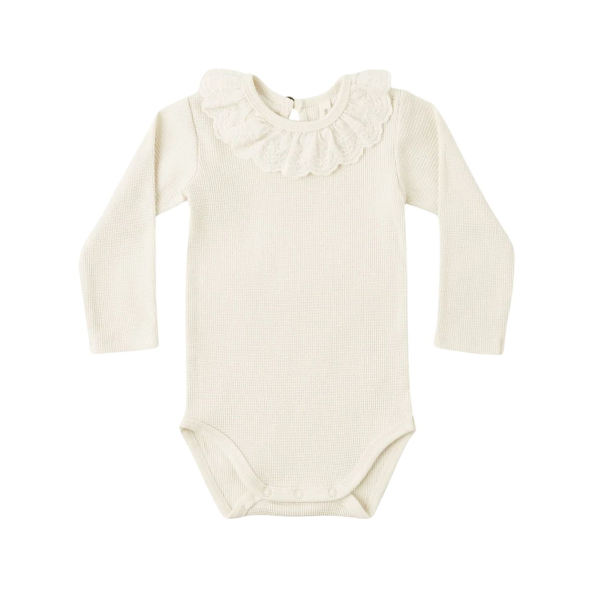 A long-sleeve baby bodysuit in a natural beige colorway, featuring a delicate ruffled collar and snap closures at the inseam, laid flat against a solid white background.