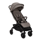 Nuna TRVL 360 lightweight travel stroller in Cedar brown, shown in a three-quarters front view against a clean white background. The stroller features an extended sun canopy, a brown leatherette-accented pushbar and rotating armbar, a harness with a magnetic buckle, 360-degree swivel wheels, and an under-seat storage basket.