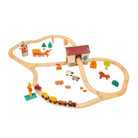 A wooden train set with tracks arranged in an oval layout featuring a red barn, a windmill, green trees, and various farm animals including sheep, pigs, and horses, accompanied by a small wooden train with yellow and red carriages.