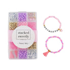 Princess Party DIY Bracelet Kit featuring a compartment storage box filled with colorful beads, alphabet letter beads, and charms next to two completed pink, purple, and gold beaded bracelets, including one spelling "PRINCESS" with a small crown and tassel charm.