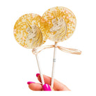 Two unicorn-themed lollipops on sticks held by a hand with pink nail polish against a white background.