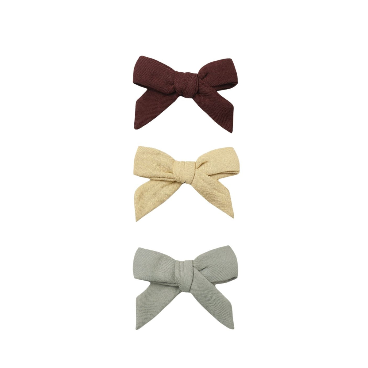 Three fabric bow hair clips in dark brown, light beige, and sage green, arranged vertically on a plain white background.