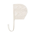 An off-white knit baby bonnet with a chevron pattern and a long tie strap, shown against a plain white background.