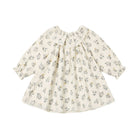 A long-sleeve baby dress with a ruffled Peter Pan collar, featuring a delicate cream base with a small all-over floral print in muted green and yellow.