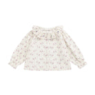 A long-sleeve blouse for toddlers or girls, featuring a ruffled collar, puff sleeves, and a delicate pink floral print on a cream-colored fabric, shown against a plain white background.