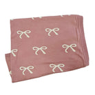 Pink blanket with white bow patterns on a white background