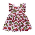 A children's sleeveless dress with ruffled shoulder straps and a smocked waist, featuring an allover raspberry print on a light pink background. The print includes red raspberries and green leaves, shown against a plain white background.