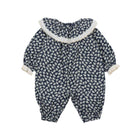 A baby snowsuit or one-piece jumpsuit with a navy blue and white floral pattern, featuring a white faux-fur collar and white cuffs, shown against a plain white background.
