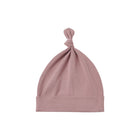 A dusty pink knit baby beanie hat with a knotted top and folded cuff, shown on a plain white background.
