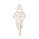 A baby sleep suit and matching knotted hat set in a warm off-white/cream color with a delicate, all-over muted brown floral print, displayed on a solid white background.