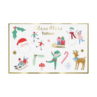 A sheet of Christmas-themed temporary tattoos featuring festive illustrations such as Santa Claus, a snowman, an elf, a reindeer, candy canes, a mushroom, holly, stars, and the text 'Meri Meri Tattoos' on a white background with a gold border.