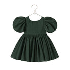 A dark forest green toddler dress with voluminous puff sleeves and a gathered flared skirt, hanging on a simple metal hanger against a plain white background.