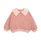 A children's long-sleeve knit top with horizontal stripes in dusty pink and terracotta orange, featuring a solid pale pink collar, cuffs, and hem, shown on a plain white background.