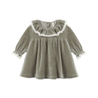 A long-sleeve velour baby dress in a rich spruce green shade, featuring an empire waist silhouette and a white lace-trimmed ruffled collar and cuffs.