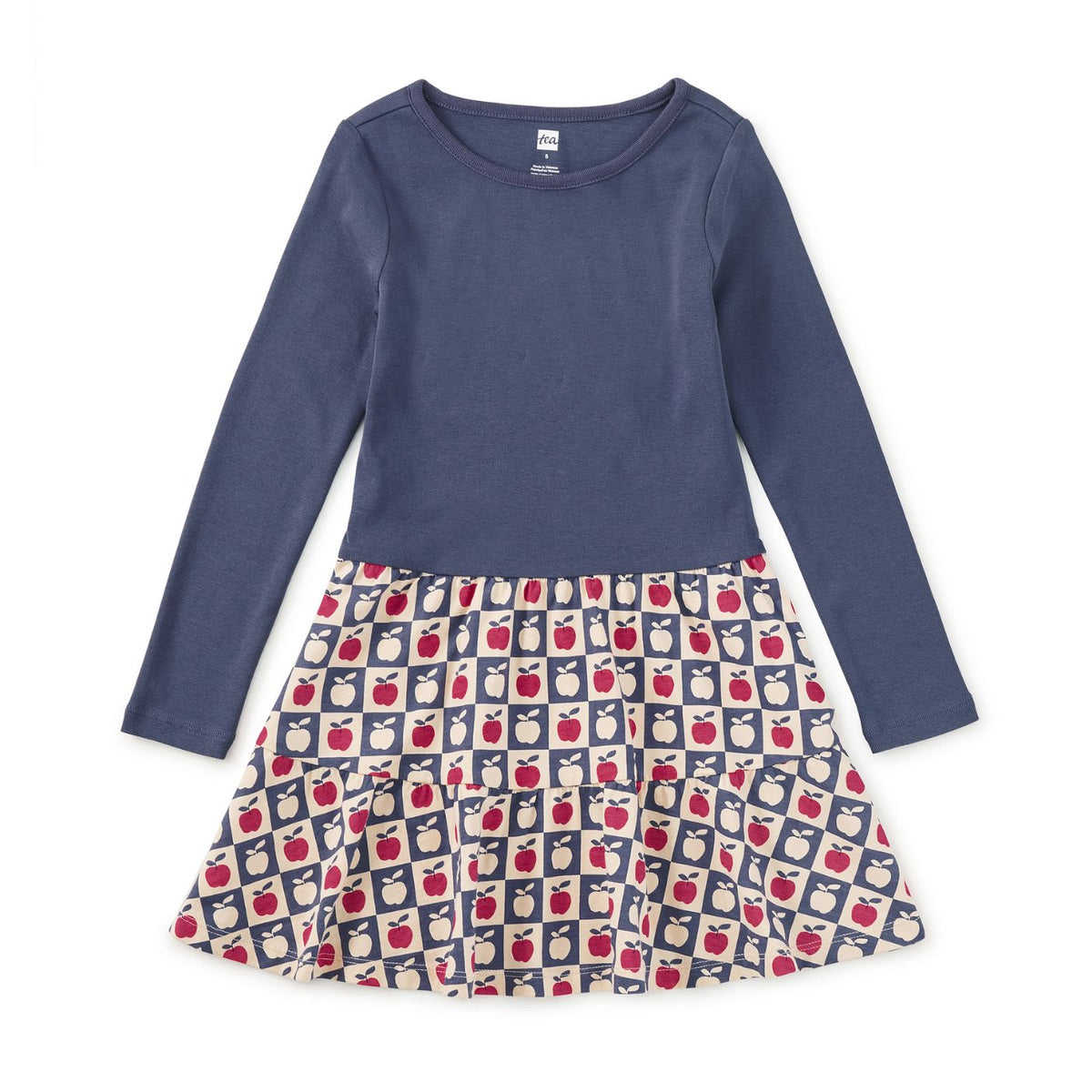 A girls' long-sleeve dress with a solid navy blue top and a tiered skirt featuring a repeating apple print on a navy and cream background.