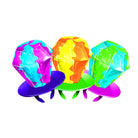 Three colorful, faceted gem-like objects displayed on small round stands against a plain white background.