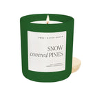 Candle with a green container and 'Snow Covered Pines' label on a white background
