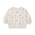A cream-colored long-sleeve sweatshirt for toddlers, featuring an all-over print of small brown leaves, white flowers, and tiny dark stars, displayed against a solid white background.