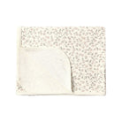 A folded baby blanket featuring a delicate, small-scale floral and leaf pattern in muted pink and gray on an off-white background, with a solid off-white reverse side.