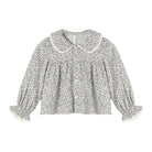 A long-sleeve blouse with a dense gray and white floral print, featuring a Peter Pan collar, gathered front, and ruffled cuffs, shown flat on a white background.