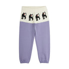 A pair of color-block sweatpants with a light purple lower half and an off-white upper half featuring four black cat illustrations. The pants have elastic waistbands and cuffed ankles.