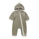 Front view of a long-sleeve hooded fleece baby jumpsuit in a rich spruce green shade, featuring a diagonal front zipper, white ribbed cuffs at the wrists and ankles, and a hood topped with a small white pom-pom against a white background.
