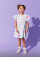 Young girl wearing a colorful dress with a plain purple background